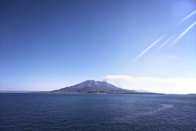 Scenic view of sea and mountains against blue sky