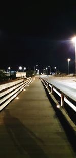 Empty road along illuminated street lights at night