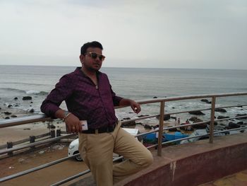 Portrait of man standing on railing against sea