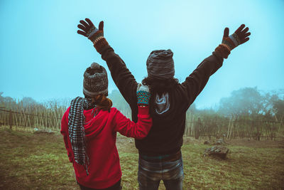 Friends standing on field by land against sky