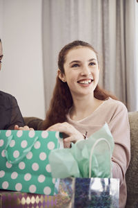 Smiling girl looking away while holding birthday present at home