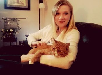 Portrait of smiling young woman with cat at home