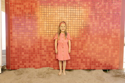 Happy cute girl standing in front of wall at beach
