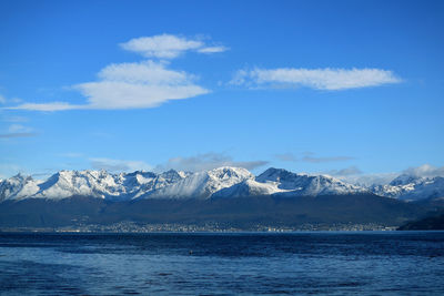 Scenic view of sea and snowcapped mountains against blue sky