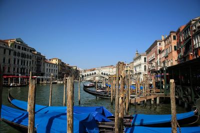 Boats moored at canal against clear blue sky