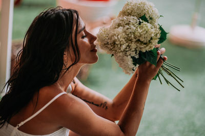 Side view of young woman holding flower