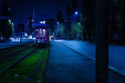 Illuminated railroad tracks against sky at night