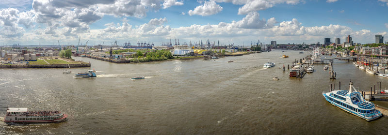 Sailboats moored in harbor by city against sky