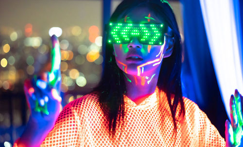 Portrait of woman with illuminated lighting equipment at night