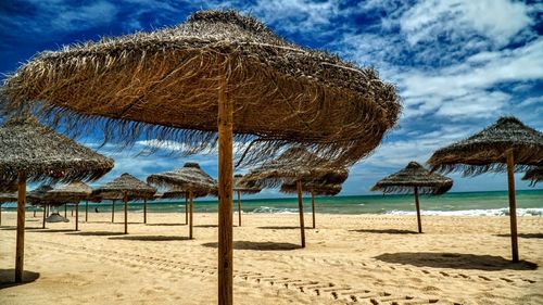 Thatched roof on beach against sky