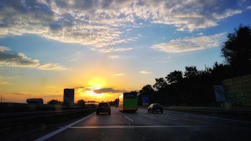 Cars on road against sky during sunset