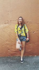 Portrait of woman smiling while leaning on wall