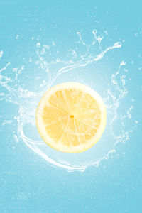 Lemon slice with water splash isolated on blue blackground. vertical format.