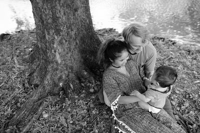 Full length of mother and daughter on tree trunk