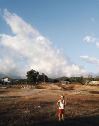 Boy wearing lion headwear while standing on field against sky