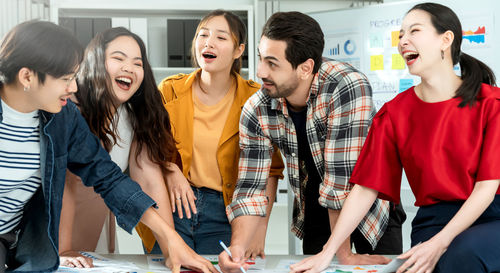 Cheerful colleagues discussing on desk in office