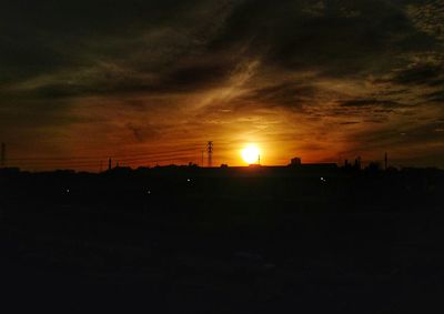 Scenic view of silhouette field against orange sky