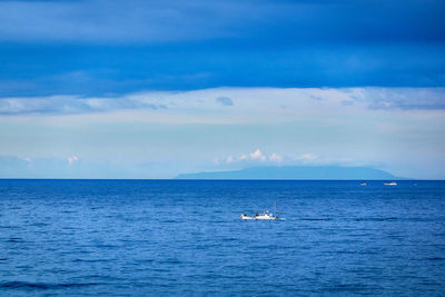 Scenic view of sea with a boat against cloudy sky