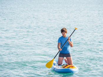Sportsman on knees paddling on stand up paddleboard. sup surfing. outdoor recreation.