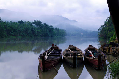 Boats moored on lake against sky