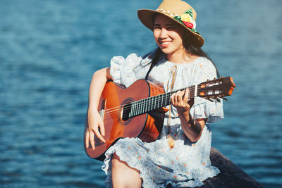 Young woman playing guitar in sea