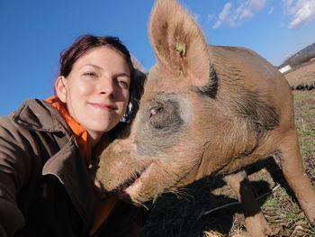 Portrait of young woman with pig on grassy field