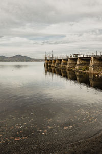 Wooden posts in lake against sky