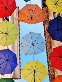 Low angle view of multi colored umbrellas hanging against sky