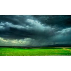 Scenic view of grassy field against cloudy sky