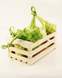Close-up of green chili peppers in basket against white background