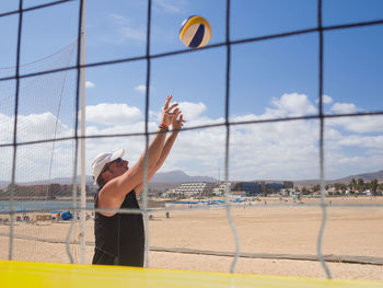 Man playing with ball on beach against sky