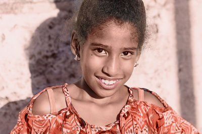 Portrait of smiling girl against wall