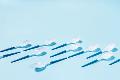 Beautiful and dangerous plastic spoons with blue handles on blue background.