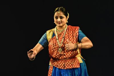 Smiling woman performing kathak against black background