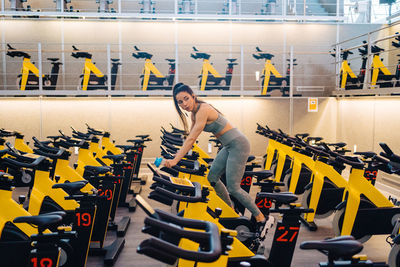 Side view of young female athlete on cardio bike in modern gym