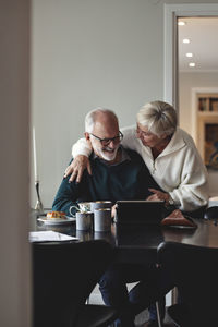 Smiling senior couple talking by dining table in living room