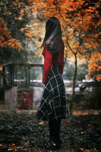 Rear view of woman standing by tree during autumn