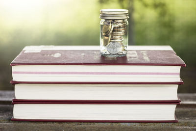 Close-up of coins in jar over books on table