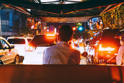 Rear view of man on illuminated street at night