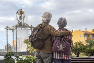 Rear view of couple looking at fountain against sky