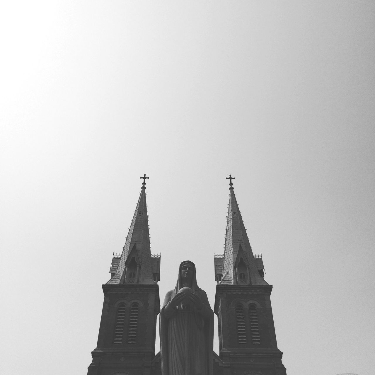 religion, architecture, clear sky, built structure, copy space, spirituality, place of worship, building exterior, statue, human representation, low angle view, church, sculpture, famous place, standing