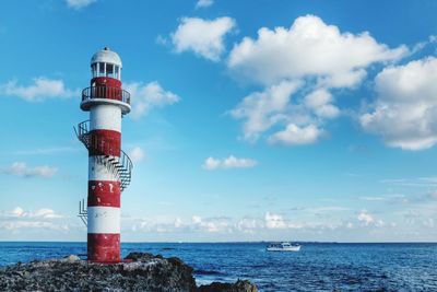 Lighthouse by sea against sky