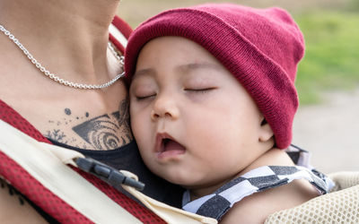 Close-up of cute baby girl sleeping on mother chest