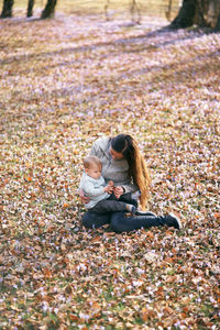 Rear view of couple sitting on autumn leaves