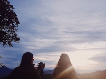 Low section of woman against sky during sunset