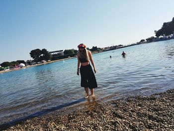 Rear view of man and woman walking on sea against clear sky