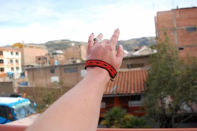 Close-up of human hand against buildings in town