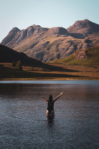 Rear view of man in lake against mountain range