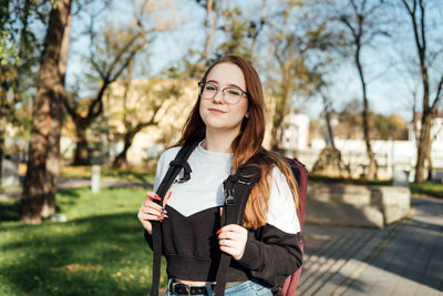 Choosing a university, college. female college student with books and laptop outdoors. redhead