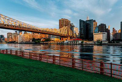 Bridge over river by buildings against sky in city